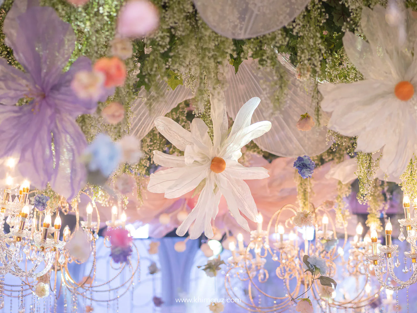 Oversized floral designs hang elegantly from the ceiling enhancing the spring garden-inspired wedding reception