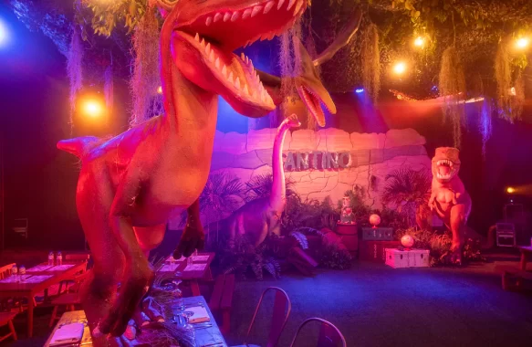 Velociraptors playfully perch on the tables on dinosaur themed 1st birthday party