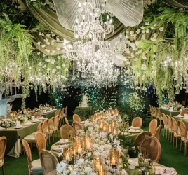 a harmony of lush greens and soft whites sets the tone complemented by elegant floral chandeliers and glowing candles at the wedding reception