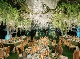 a harmony of lush greens and soft whites sets the tone complemented by elegant floral chandeliers and glowing candles at the wedding reception