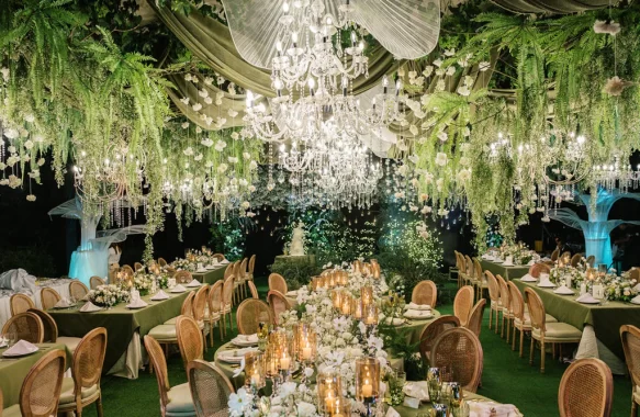 a harmony of lush greens and soft whites sets the tone complemented by elegant floral chandeliers and glowing candles at the wedding reception