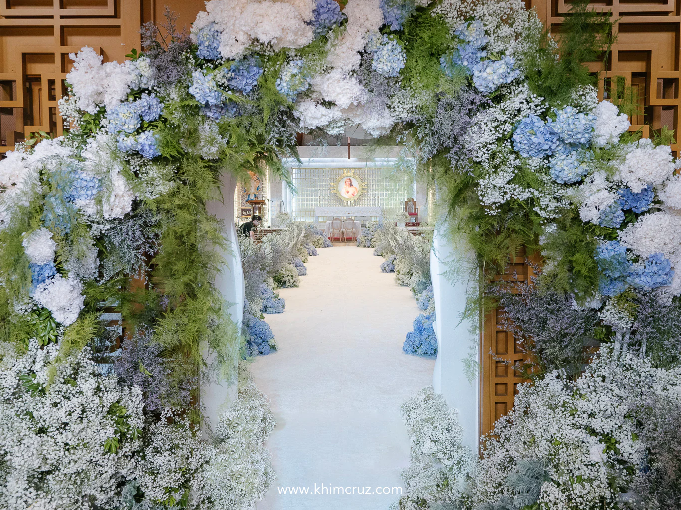 arch made of white and blue hydrangeas greenery babys breath as backdrop for wedding ceremony entrance