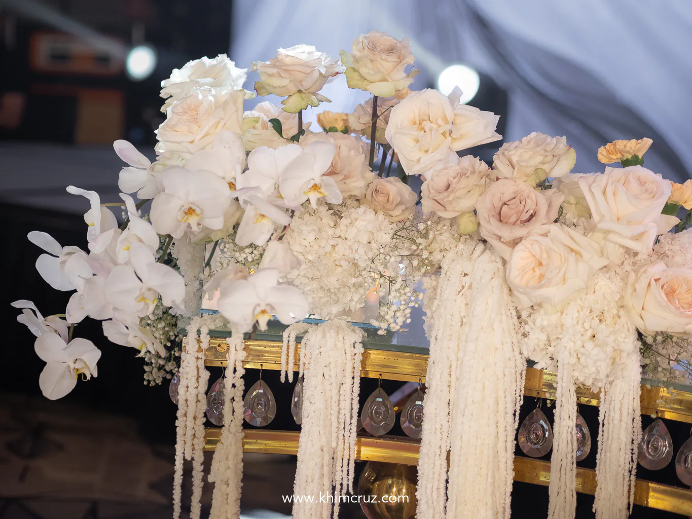 phalaenopsis roses and baby's breath in soft pastel tones on an ornate table at the wedding reception